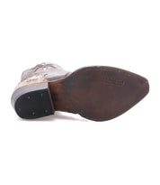 The Bed Stu Frio features a pointed toe, leather sole with visible stitching, and a rubber heel with small nails. Antiqued brass studs accent this Western bootie, shown from the bottom for detail.