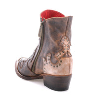 The Bed Stu Frio is a brown and tan leather Western bootie with floral cutouts, decorative stitching, brass studs, a side zipper, and a low heel, shown on a white background.