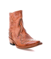 The Bed Stu Frio is a brown leather Western bootie with decorative stitching, floral cutouts, brass studs, a low stacked heel, and a pointed toe, displayed against a white background.
