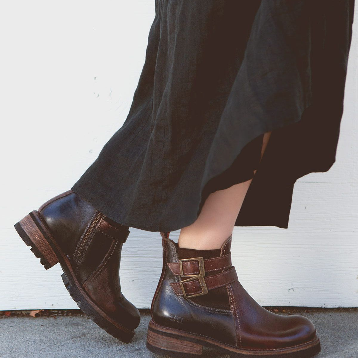 A person wearing a long dark skirt and Bed Stu's stylish Ginger II dark brown Chelsea ankle boots stands against a light-colored background.