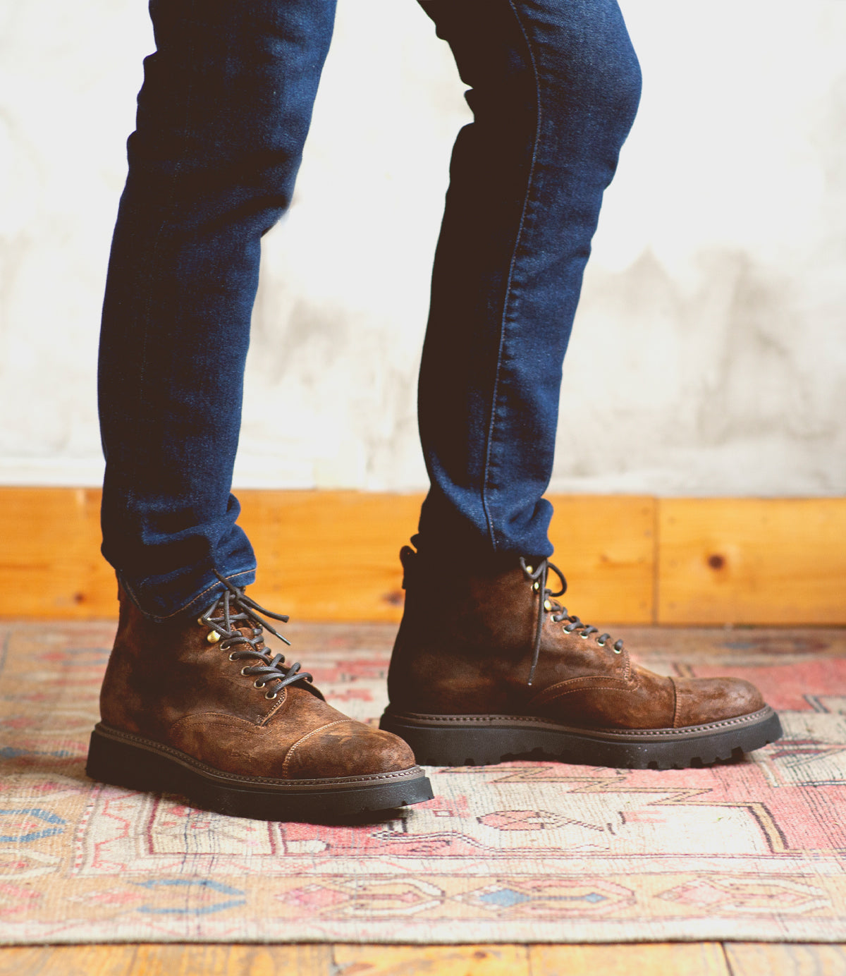 A man in Bed Stu Goer boots and jeans standing on a rug.