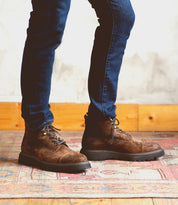 A man in Bed Stu Goer boots and jeans standing on a rug.