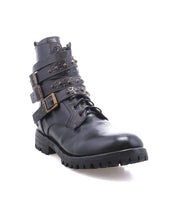 The Bed Stu Grab is a black leather combat-style boot featuring studded buckle straps, laces, and a rugged Vibram rubber lug sole, shown on a white background.