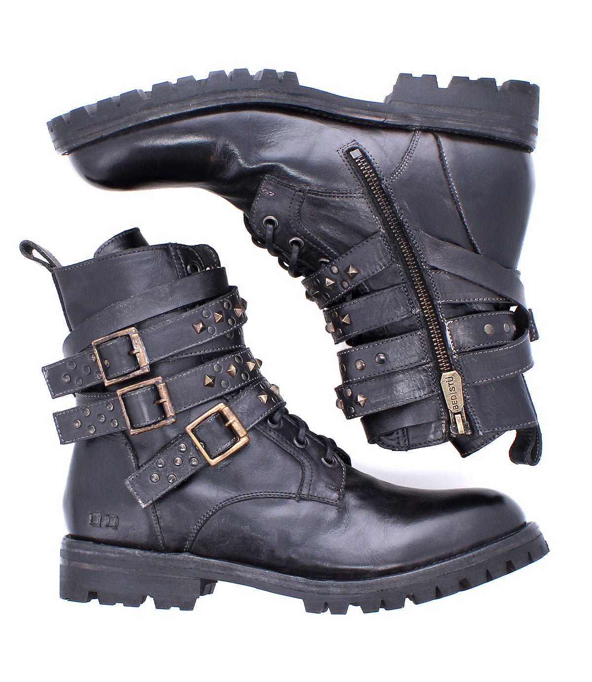 The Bed Stu Grab boots are black leather combat-inspired footwear with studded buckle straps, side zippers, and thick treaded soles—shown with one boot upright and the other on its side.