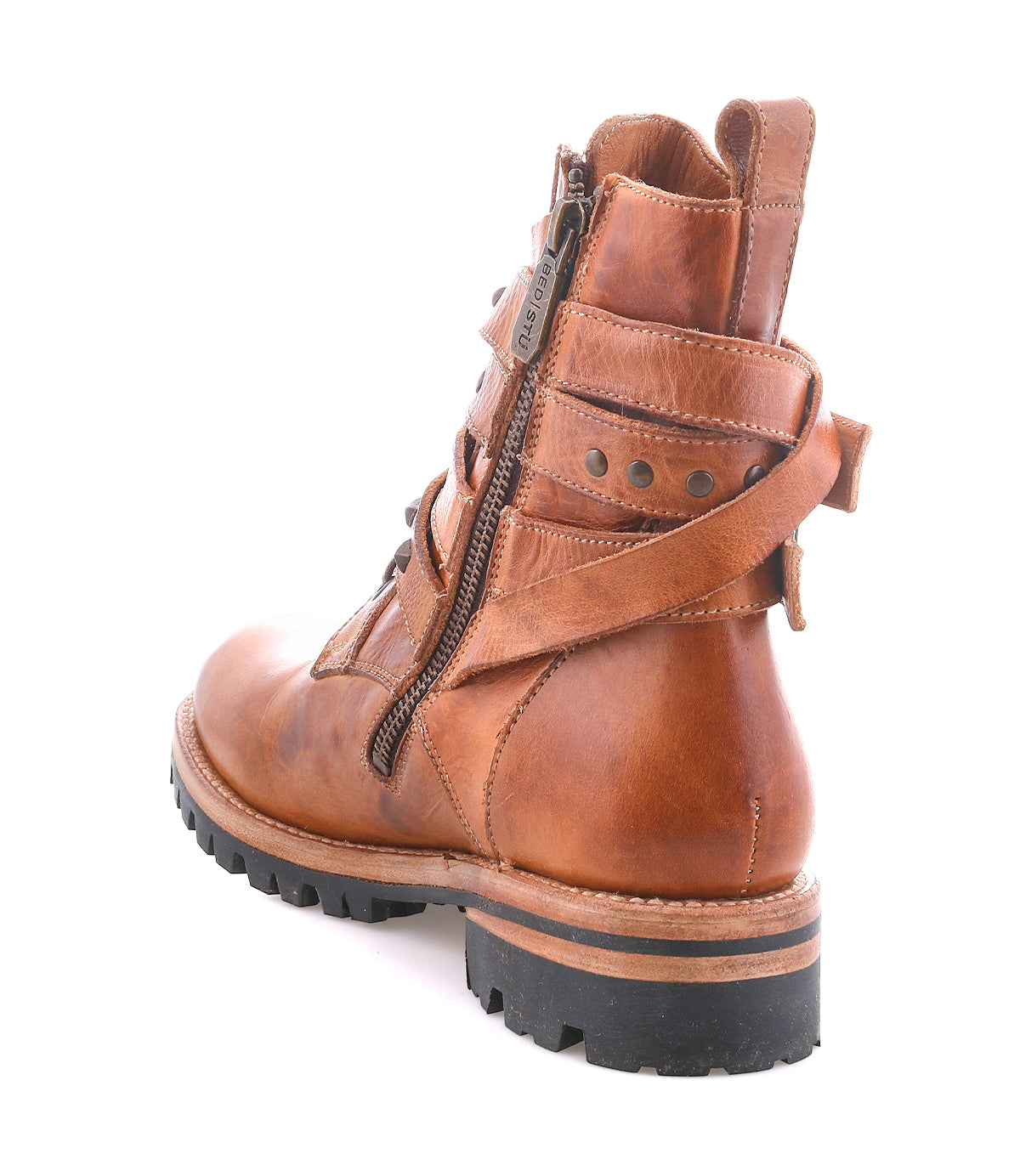 The Bed Stu Grab is a brown leather combat-inspired ankle boot with Vibram lug sole, side zipper, studded buckle straps, and metal studs, shown from the back and side on a white background.