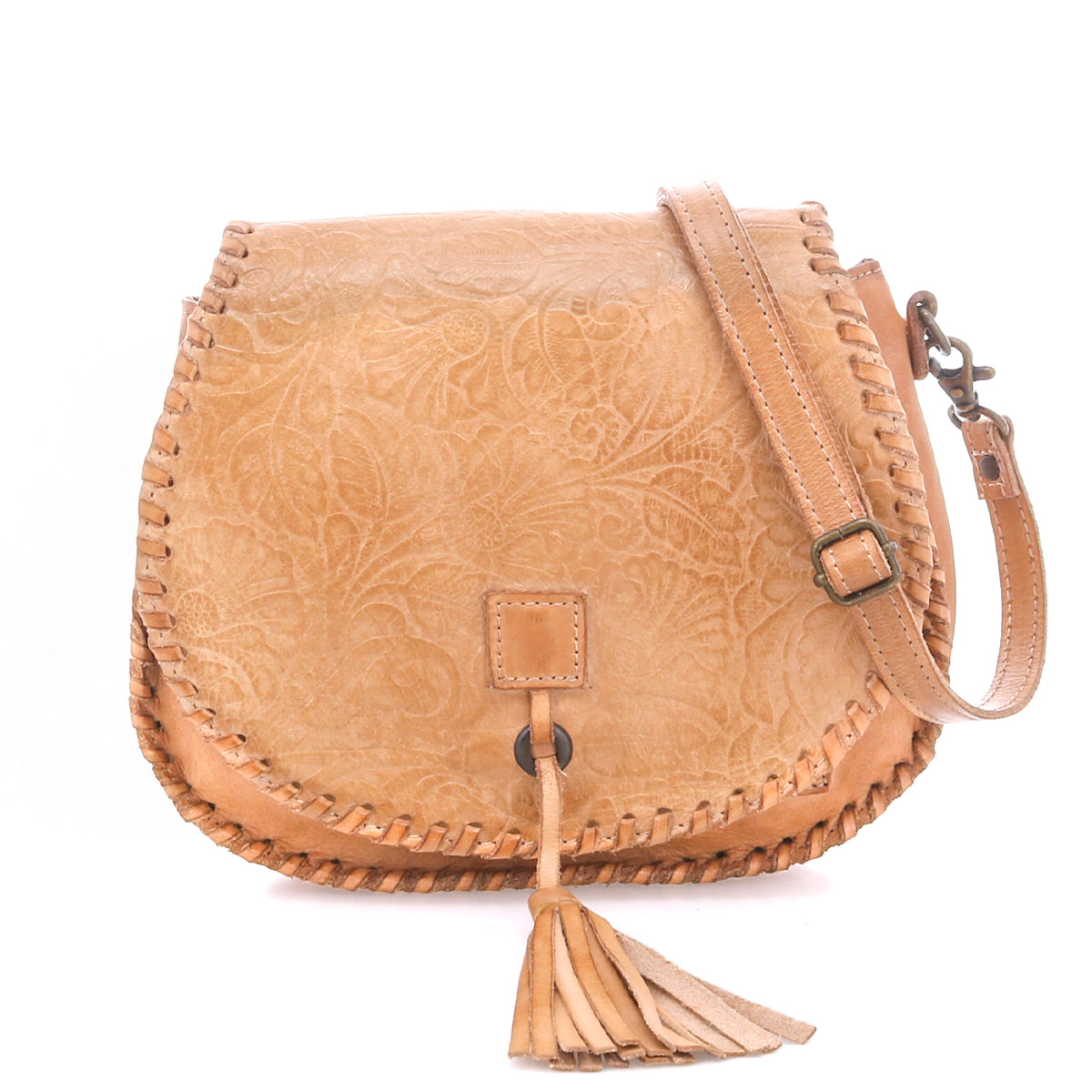 The Bed Stu Half Moon EM is a light brown leather crossbody purse featuring an embossed foliage pattern, whipstitch edges, adjustable strap, and a front tassel detail.