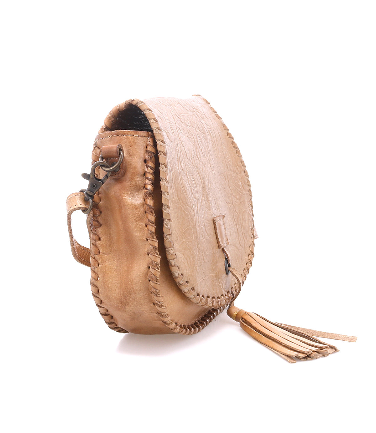 The Bed Stu Half Moon EM is a small tan leather crossbody purse with a flap closure, visible stitching, metal hardware, a tassel accent, and an elegant embossed foliage pattern for texture.