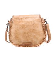 The Bed Stu Half Moon EM is a tan leather saddlebag crossbody purse featuring an embossed foliage pattern, braided edges, and an adjustable shoulder strap.