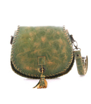 The Bed Stu Half Moon is a green leather crossbody purse featuring visible stitching, a flap closure, tassel detail, and an adjustable strap placed beside it.