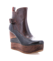 The Harmonious by Bed Stu is a dark brown leather ankle boot with a sculptural wood platform wedge, side buckle, decorative stitching, and a refined leather interior.