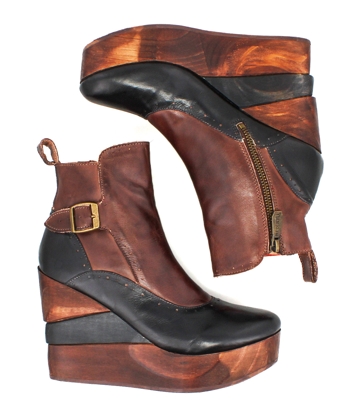 The Bed Stu Harmonious is a pair of brown and black leather Platform Wedge Ankle Boots featuring a sculptural wood wedge, side zipper, decorative buckle, and chic brogue-style perforations.