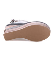 A close-up of the sole of the Bed Stu Harmonious sandal, showcasing its thick layered platform, sculptural wood wedge, and buckle strap, viewed from the bottom.