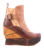 The Bed Stu Harmonious is a brown leather platform wedge ankle boot with a side buckle, a thick sculptural wood wedge heel, and a rich red leather interior.