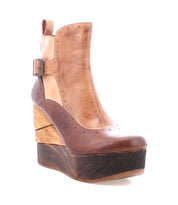 The Bed Stu Harmonious is a brown leather platform wedge ankle boot with a sculptural wood wedge heel, layered wooden platform, ankle buckle, color block details, and red leather interior, shown on a white background.
