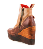 The Bed Stu Harmonious is a brown leather platform wedge ankle boot with brogue perforations, side zipper, and sculptural wood wedge sole, shown from the back angle.