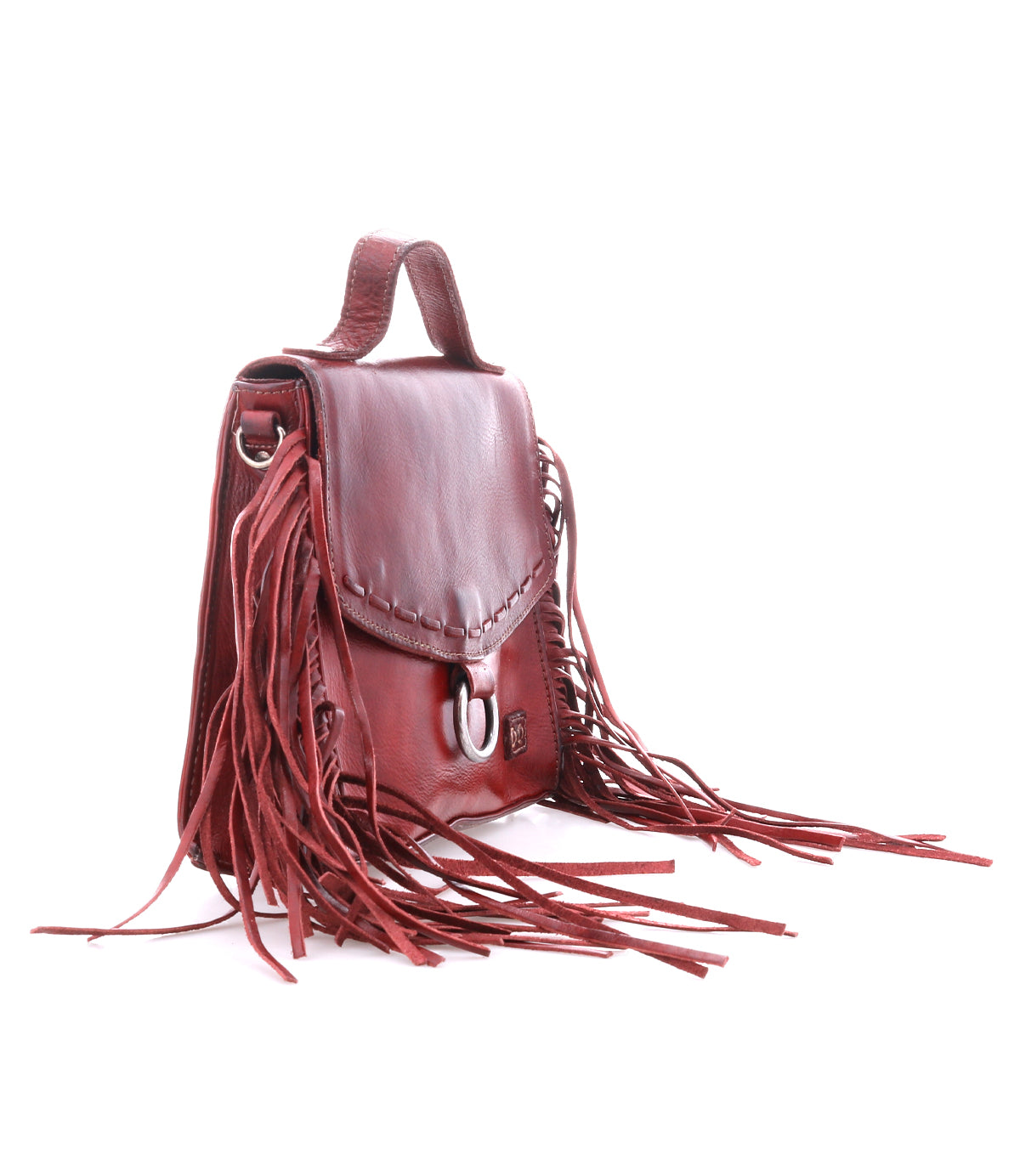 The Bed Stu Hidden is a small brown leather crossbody bag featuring a top handle, adjustable strap, front flap with metal clasp, and long fringe accents on the sides, displayed against a white background.
