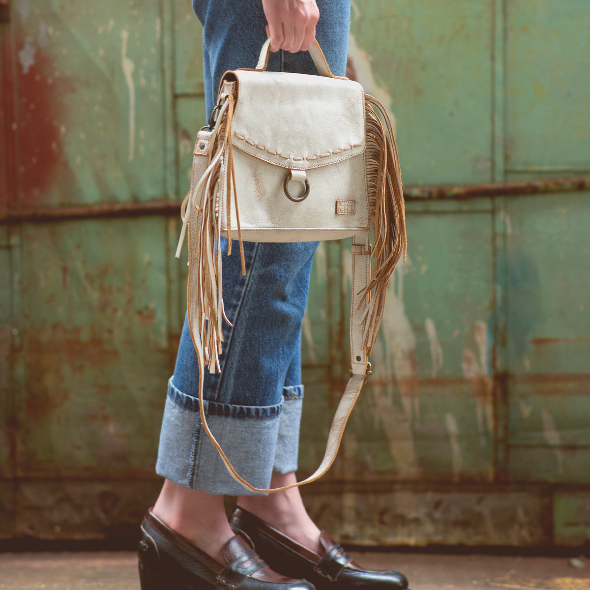 A woman is holding a white Bed Stu fringe purse.