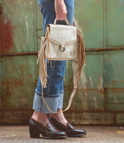 A woman is holding a white Bed Stu fringe purse.