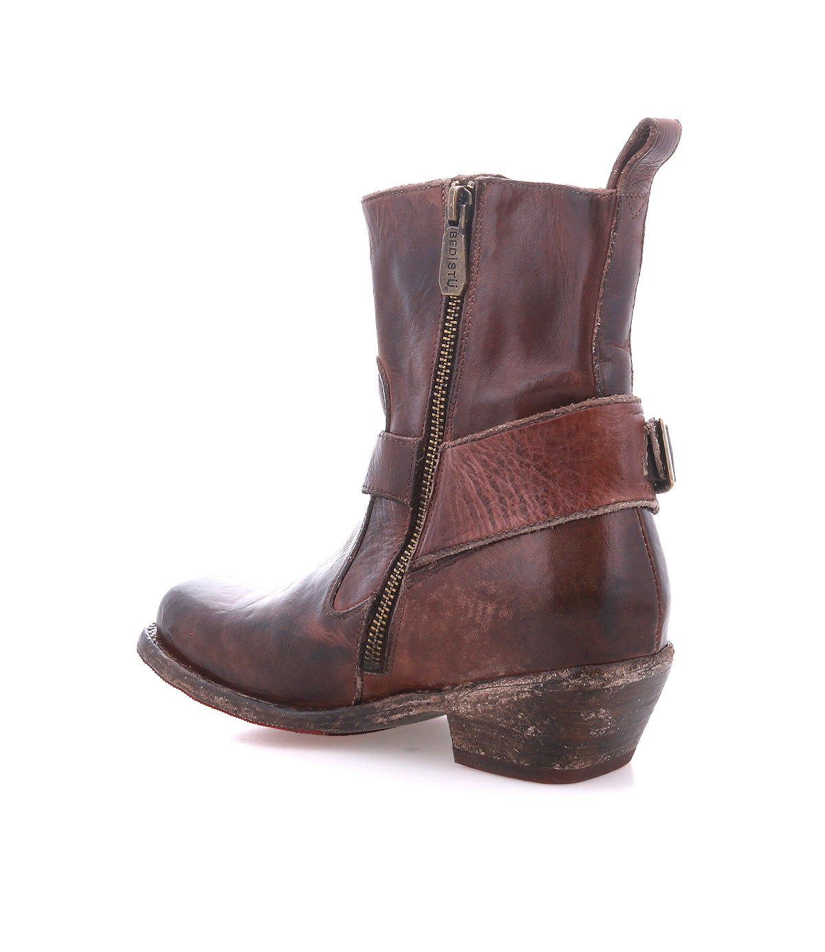 The Bed Stu Homage is a brown leather boot with a square toe, side zipper, decorative strap, and low stacked heel, shown in profile with a gently worn look.