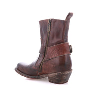 The Bed Stu Homage is a brown leather boot with a square toe, side zipper, decorative strap, and low stacked heel, shown in profile with a gently worn look.