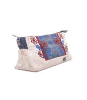 The Bed Stu Hyperbolic is a beige handcrafted leather shoulder bag featuring blue and red floral embroidery, blue accents, and a top metal zipper, shown against a white background.