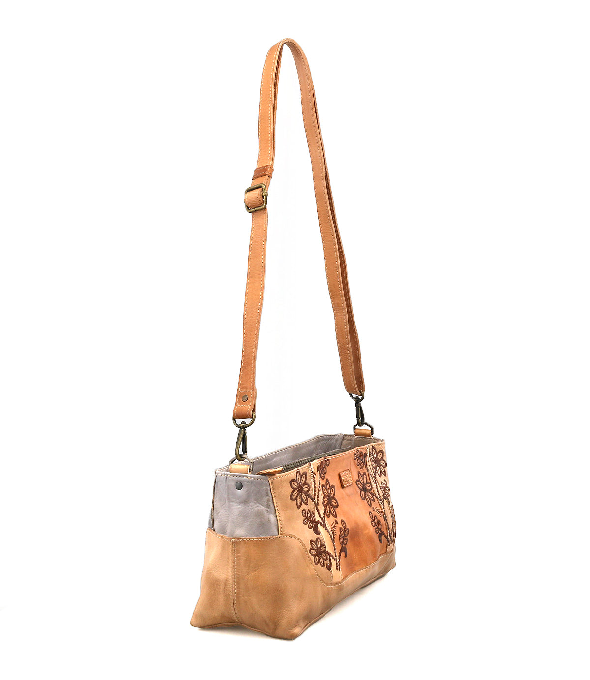 The Bed Stu Hyperbolic is a tan and gray leather shoulder bag with floral embroidery, an adjustable strap, and metal hardware that exudes handcrafted bohemian charm. Shown here against a white background.