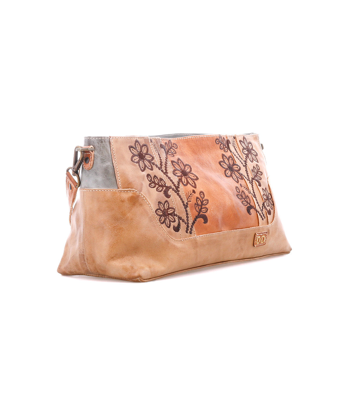 The Bed Stu Hyperbolic is a tan and light brown leather clutch bag with bohemian floral embroidery and metal hardware, shown on a white background. This handcrafted accessory brings artisanal flair to any outfit.