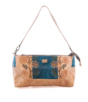 The Bed Stu Hyperbolic is a beige and teal bohemian shoulder bag with floral embroidery, handcrafted with a single strap, shown on a white background.