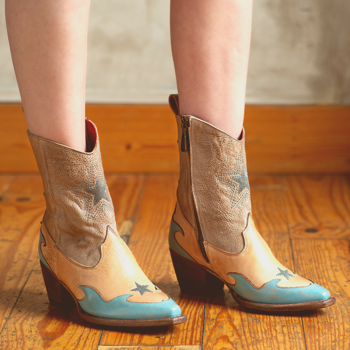 An artistically crafted pair of Hyperspeed boots, in shades of blue and tan, by Bed Stu, worn by a woman.
