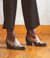 A woman wearing a handcrafted pair of Bed Stu Hyperspeed leather boots on a wooden floor.