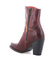 The Bed Stu Iazu is a brown handcrafted leather ankle boot with a side zipper, stacked heel, and pointed toe, shown on a white background.
