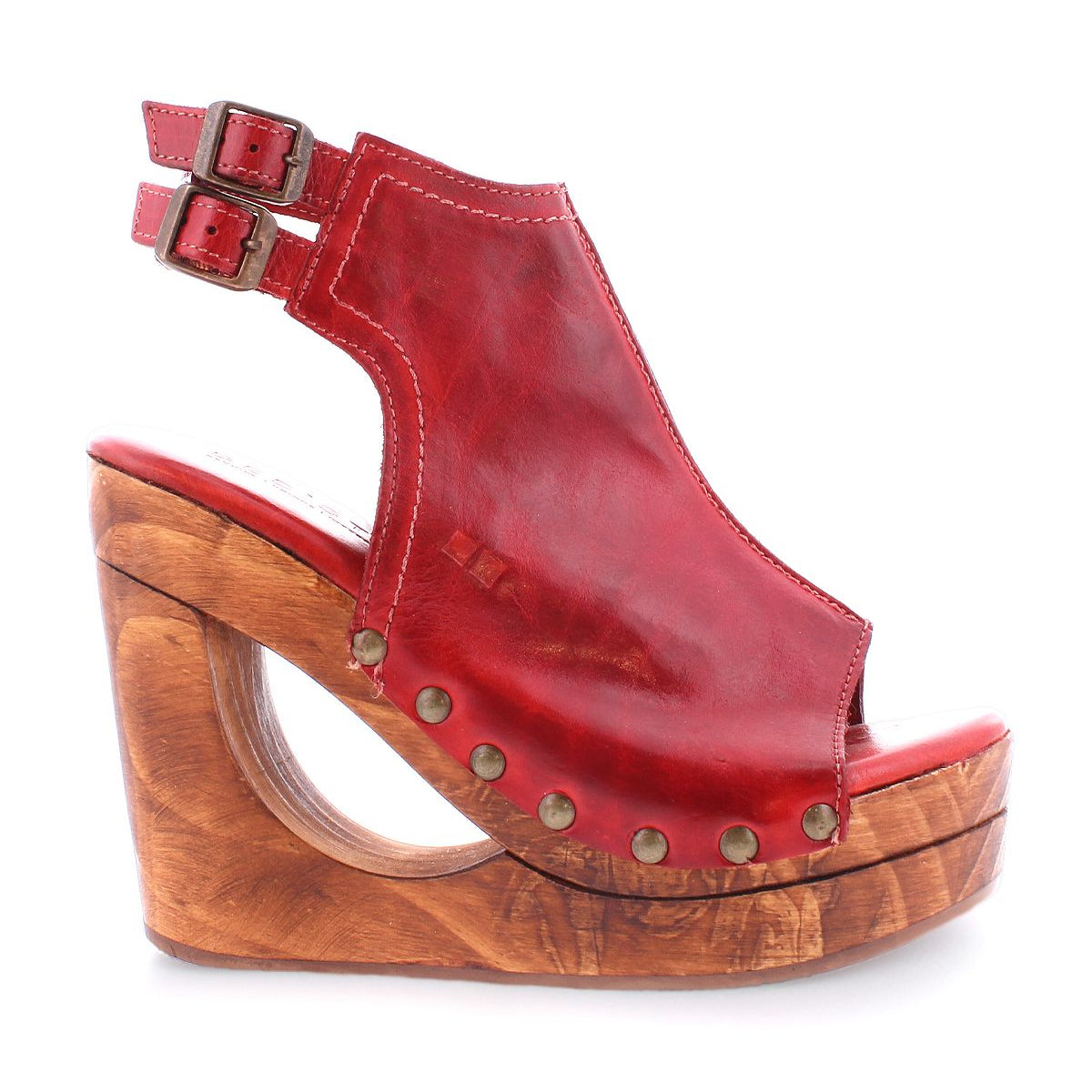 Introducing the Imelda by Bed Stu: a red leather wedge sandal with an open-toe design, incorporating double ankle straps with buckles, a wooden platform, and embellished with decorative metal studs.