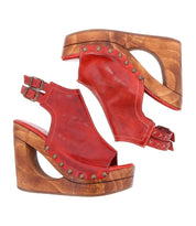 The Imelda sandals from Bed Stu are red leather wedge sandals with wooden soles, embellished with metal studs and designed with an open-toe style and sleek double buckle straps.