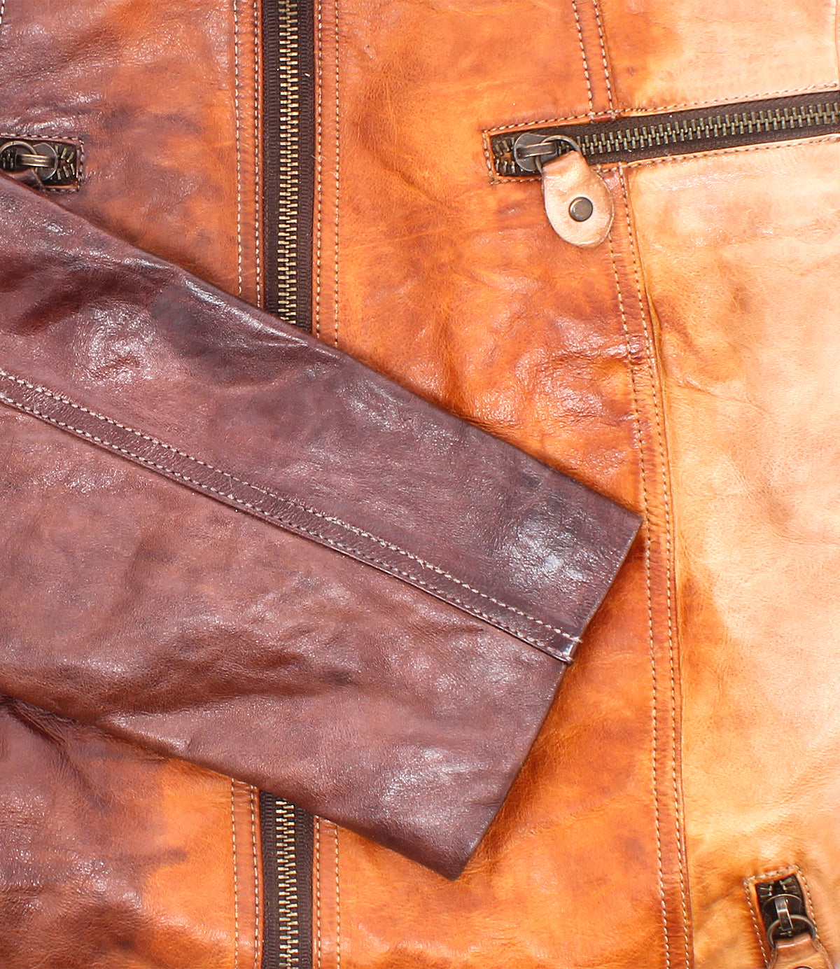 Close-up of Bed Stu's Include jacket—a handcrafted leather piece with metal zippers, detailed sleeves, and contrasting brown hues. This modern silhouette is a true statement from the iconic brand.