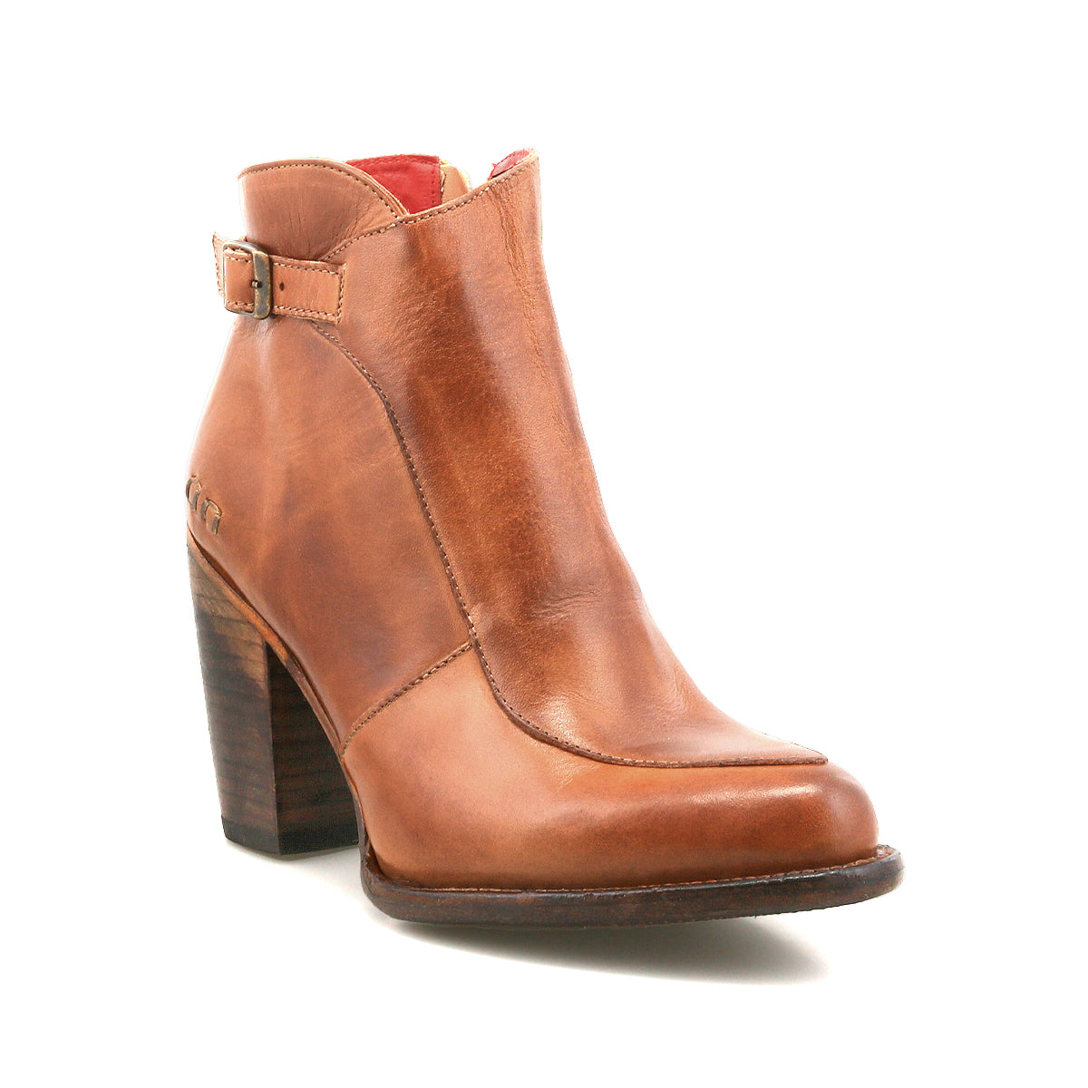 The Bed Stu Isla bootie is shown on a white background, featuring brown leather, a chunky wooden heel, vintage buckle detail, and a slightly pointed toe.