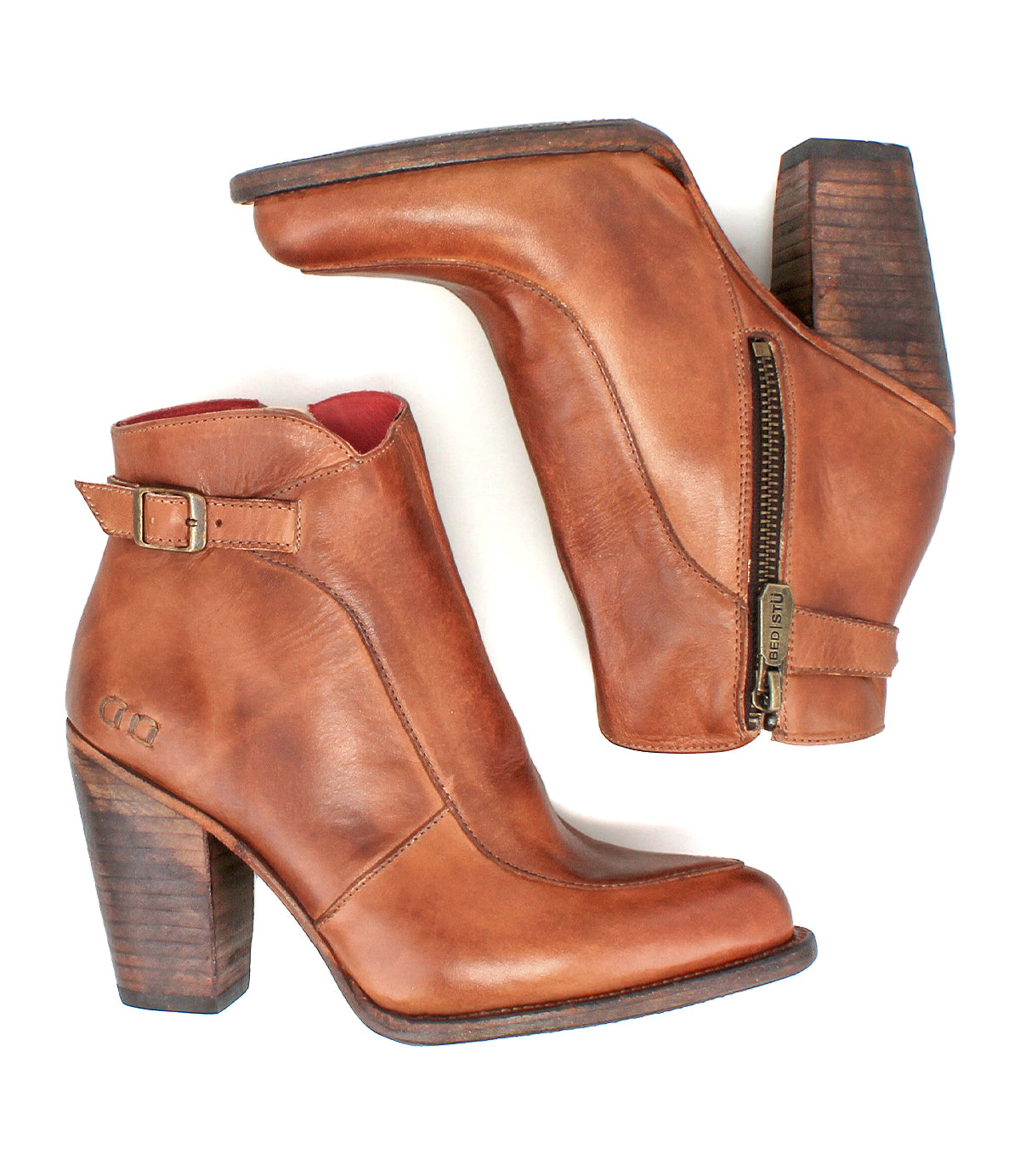 The Bed Stu Isla booties are brown leather ankle boots with side zippers, a vintage buckle, and stacked wooden heels, shown on a white background.