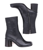 The Isodora by Bed Stu showcases Italian leather ankle boots with side zippers and chunky heels, highlighted by an elegant asymmetrical square toe design, pictured from two angles against a white background.