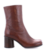 The Isodora by Bed Stu are handcrafted brown leather ankle boots that feature a chunky heel and a smooth finish, complete with an asymmetrical square toe for added flair.