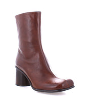 Introducing the Isodora by Bed Stu: a brown Italian leather ankle boot featuring a chunky heel and an elegantly asymmetrical square toe, showcased against a white background.