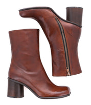 The Isodora by Bed Stu are handcrafted brown leather heeled ankle boots with a side zipper and an asymmetrical square toe, displayed from two angles.