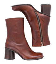 The Isodora by Bed Stu are handcrafted brown leather heeled ankle boots with a side zipper and an asymmetrical square toe, displayed from two angles.
