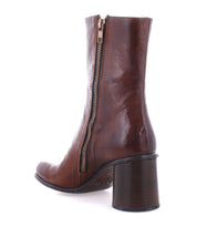 The Isodora by Bed Stu features brown handcrafted Italian leather with an asymmetrical square toe, a side zipper, and a chunky heel, viewed from the side.