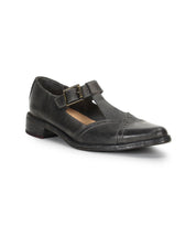 The Jenny by Bed Stu is a black leather Mary Jane casual shoe featuring a low heel, T-strap pointed toe design, cushioned insole, buckle closure, and slightly worn finish.