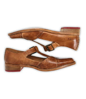 The Bed Stu Jenny shoes are a pair of brown leather Mary Janes with a T-strap, pointed toe, low wooden heels, cushioned insoles, and side buckles, displayed side by side on a white background.