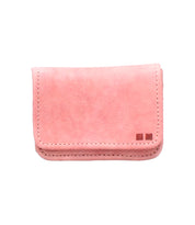 The Bed Stu Jeor is a small, rectangular, light pink leather wallet with visible stitching and two square accents in the bottom right corner—a stylish, versatile compact for everyday use.
