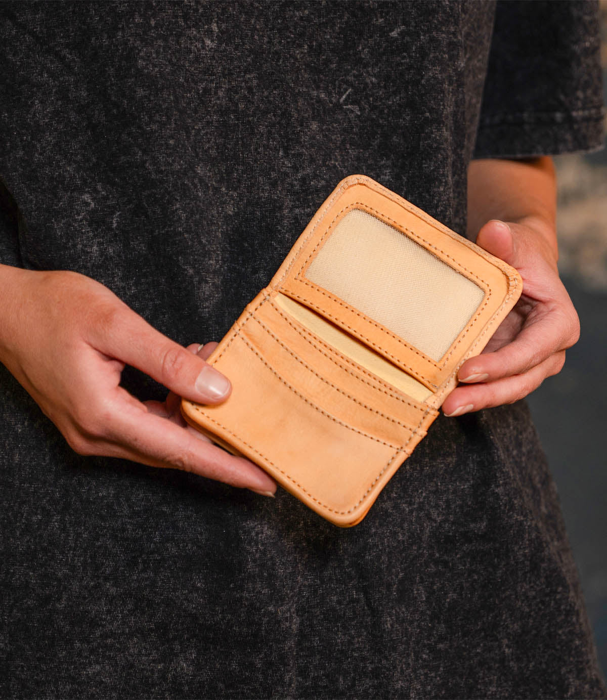 A person holds the Bed Stu Jeor, an open rustic leather card holder with visible credit card slots and a clear ID holder.