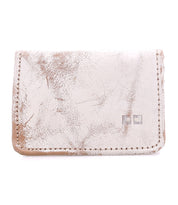 The Bed Stu Jeor is a rustic, light-colored leather card wallet with visible creases, two metallic square accents on the front, and multiple slots for everyday credit card storage.