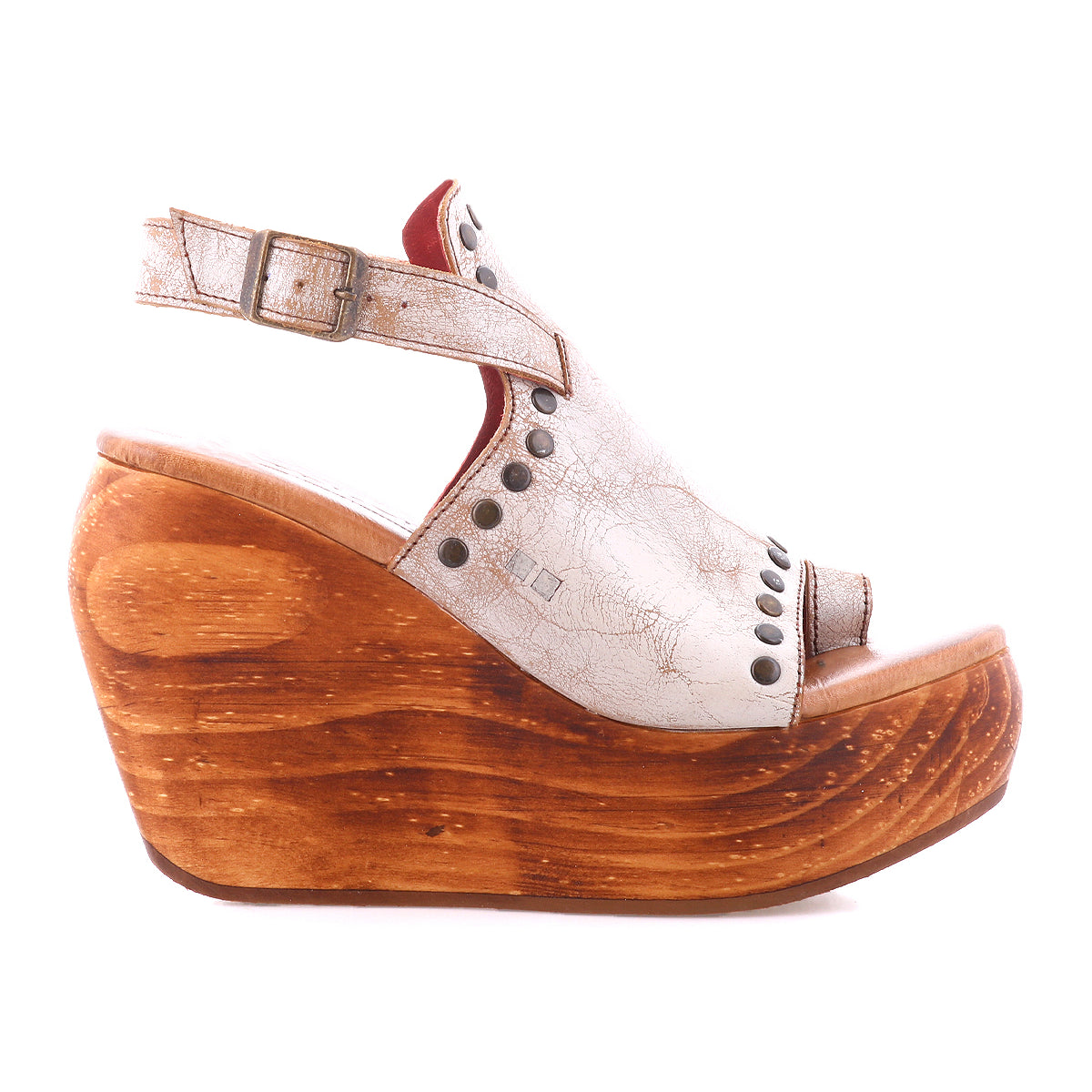 The Joann II by Bed Stu is a modern white leather peep-toe wedge sandal with a wooden platform sole, adjustable back strap, and metal stud accents.