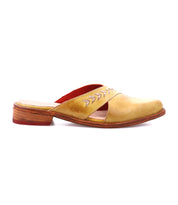 The Bed Stu Jockey is a yellow-brown leather slip-on mule featuring a wooden sole, red interior lining, cut-out sides, pointed toe, and decorative stitching for a sleek look.