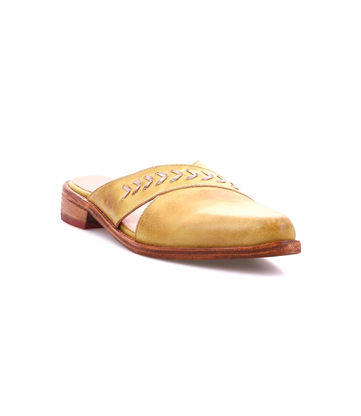The Bed Stu Jockey is a yellow leather slip-on shoe featuring a pointed toe, low wooden heel, and decorative stitching on the upper, displayed against a white background.